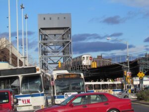 A red car is parked in front of some buses