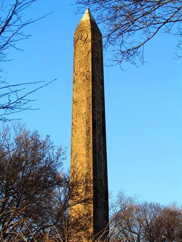 A tall stone pillar in the middle of a park.