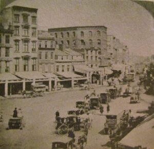 A vintage photo of people riding in carts down the street