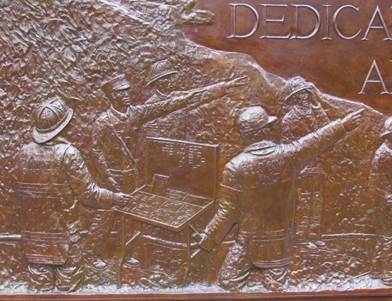 A bronze plaque with soldiers in the background.
