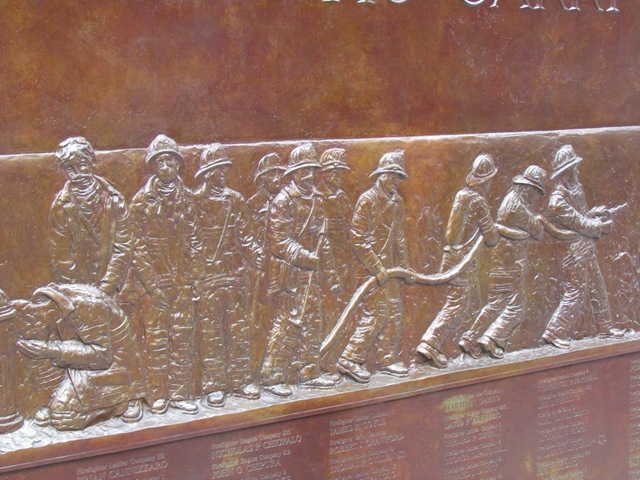 A bronze sculpture of people in uniform with fire hoses.