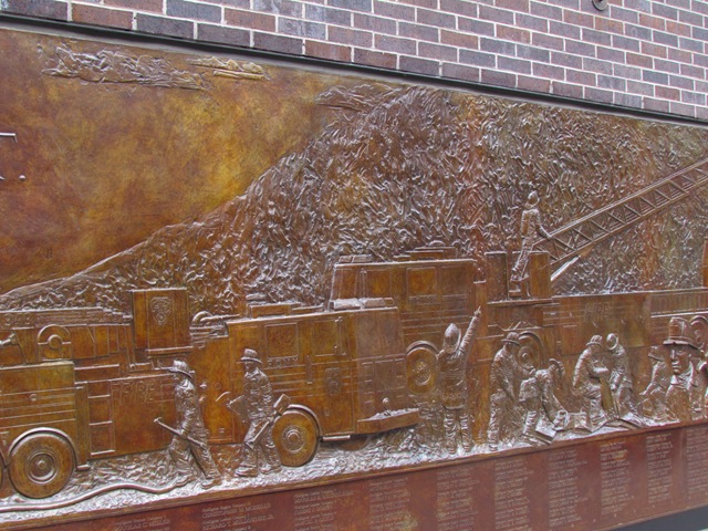A large metal sculpture of people working on a fire truck.