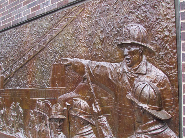 A bronze statue of a fireman pointing to the side.